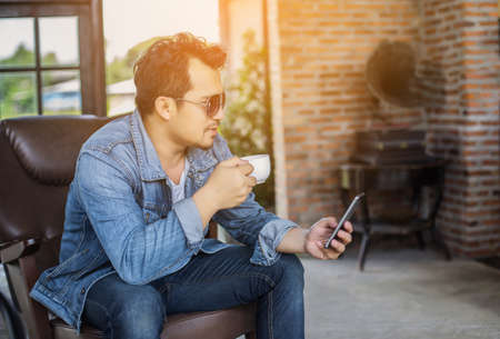 Young man with smartphone smiling relaxing at cafe.の写真素材