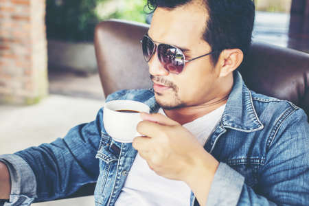 Young man with smartphone smiling relaxing at cafe.の写真素材