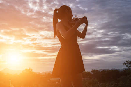 Young woman playing the violin With mountains in the backgroundの写真素材