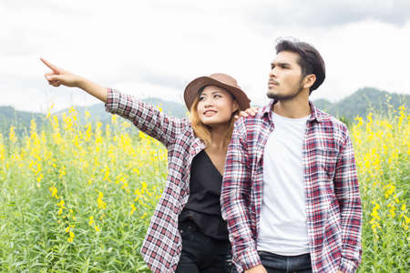 Young hipster couple relaxing in yellow flower field at summer. Enjoying with nature.の写真素材