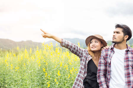 Young hipster couple relaxing in yellow flower field at summer. Enjoying with nature.の写真素材