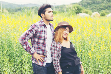Young hipster couple relaxing in yellow flower field at summer. Enjoying with nature.の写真素材