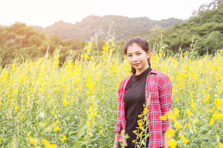 Young beautiful woman standing in the flower field enjoyment.