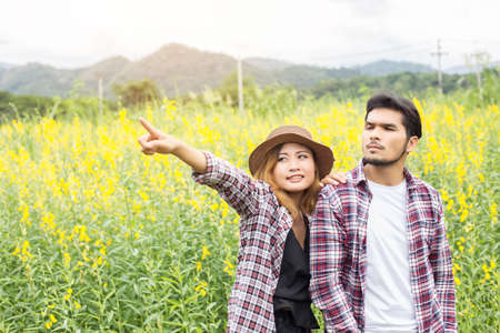 Young hipster couple relaxing in yellow flower field at summer. Enjoying with nature.の写真素材