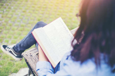 Hipster charming girl relaxing in the park while read book, Enjoy nature around.