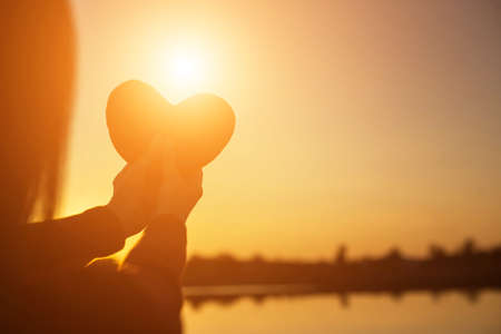 hands forming a heart shape with sunset silhouetteの写真素材