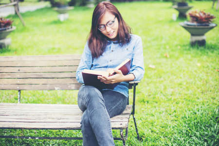 Hipster charming girl relaxing in the park while read book, Enjoy nature around.の写真素材