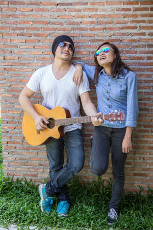 Young hipster man playing guitar to relaxing on his holiday, enjoy with natural and fresh air.の写真素材