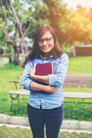 Hipster charming girl relaxing in the park while read book, Enjoy nature around.の写真素材