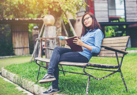Hipster charming girl relaxing in the park while read book, Enjoy nature around.の写真素材