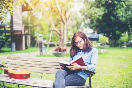 Hipster charming girl relaxing in the park while read book, Enjoy nature around.の写真素材