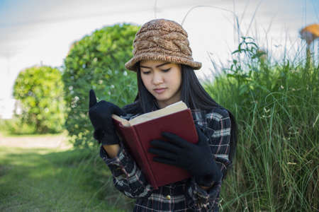 Hipster charming girl relaxing in the park while read book, Enjoy nature around.の写真素材