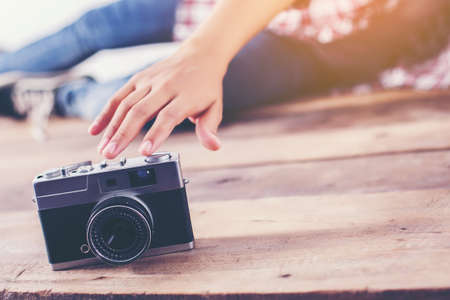 Young hipster photographer woman taking photo and look at camera sitting on wooden floor.の写真素材