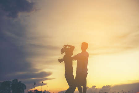 Mother encouraged her son outdoors at sunset, silhouette conceptの写真素材