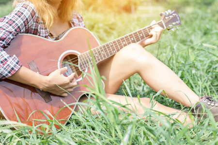 Young hipster girl sitting playing a guitar and singing.の写真素材