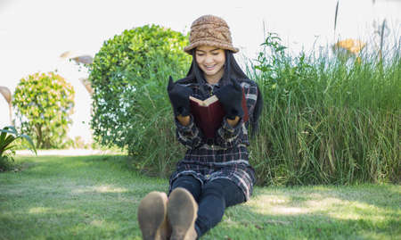 Hipster charming girl relaxing in the park while read book, Enjoy nature around.の写真素材