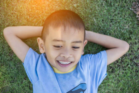 Happy mulatto boy child is smiling enjoying adopted life. Portrait of young boy in nature, park or outdoors. Concept of happy family or successful adoption or parenting.の写真素材