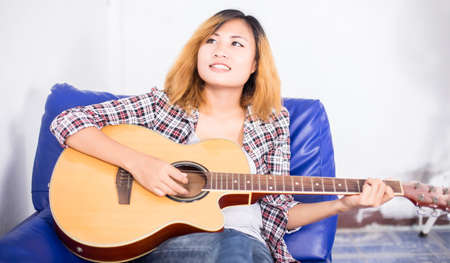 Young hipster woman playing a guitar.