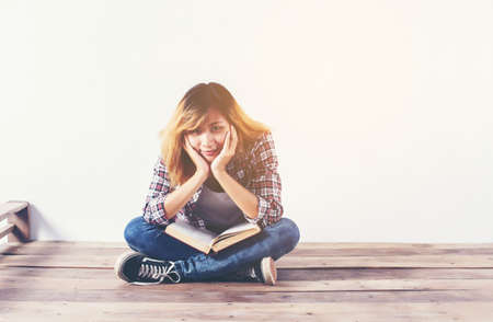 Young hipster woman holding books and pointing up on isolated white background.の写真素材