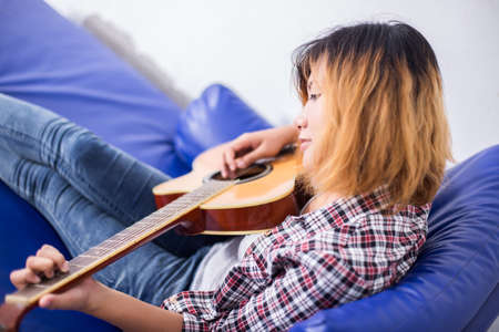 Young hipster woman playing a guitar.の写真素材
