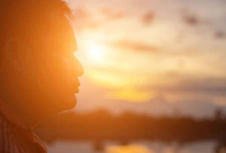 Young man is looking at the sunrise.