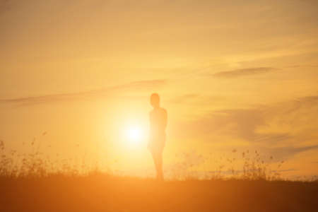 Silhouette of woman praying over beautiful sky backgroundの写真素材