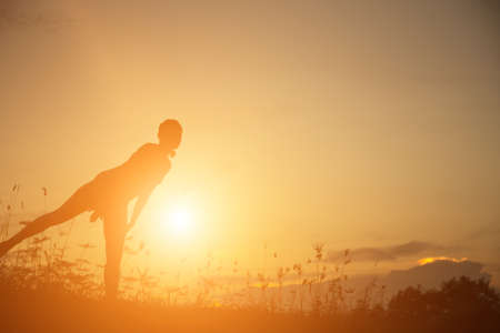 Silhouette of woman praying over beautiful sky backgroundの写真素材