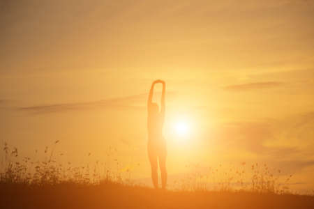 Silhouette of woman praying over beautiful sky backgroundの写真素材