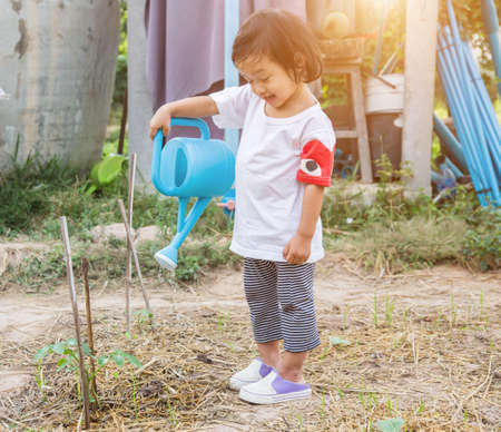 Little girl watering tree with watering potの写真素材