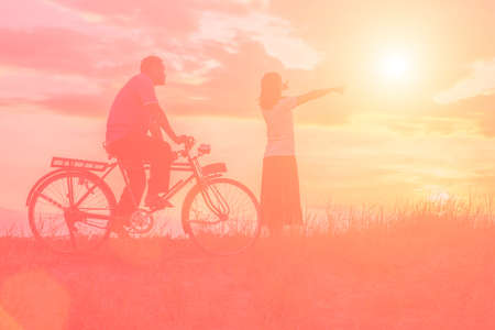 silhouette of sweet young couple in love happy time on bicycleの写真素材