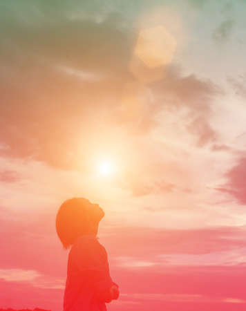 Silhouette of woman praying over beautiful sky backgroundの写真素材