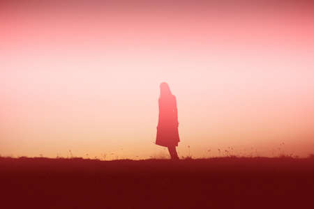 silhouette of a young woman standing aloneの写真素材