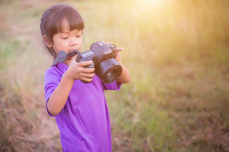 Woman with camera hiding behind the treeの写真素材
