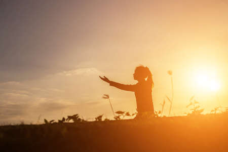 Silhouette of woman praying over beautiful sky background