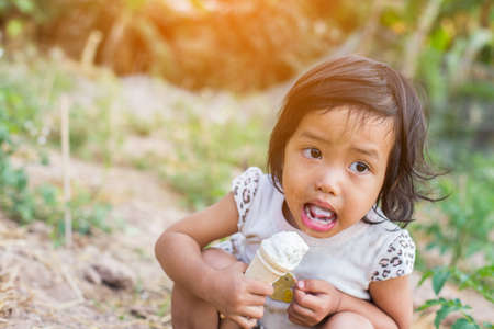Little curly girl with ice cream on colorful backgroundの写真素材