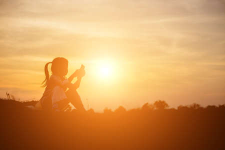 Girl at the beach texting on sunsetの写真素材