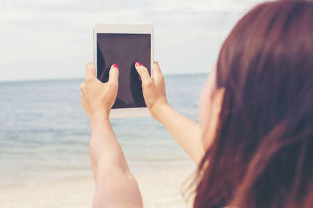 Young female sitting at cafe table with digital tablet