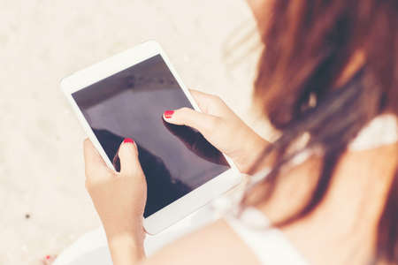 Young female sitting at cafe table with digital tablet