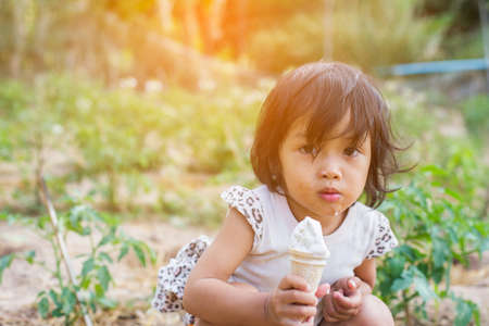Little curly girl with ice cream on colorful backgroundの写真素材