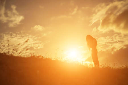 silhouette of a young woman standing aloneの写真素材