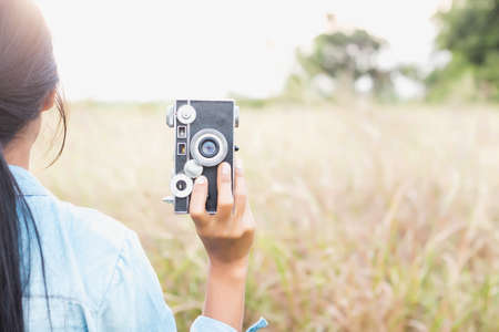 Woman photographed in a meadow with a camera.の写真素材