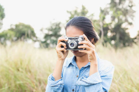 Woman photographed in a meadow with a camera.の写真素材