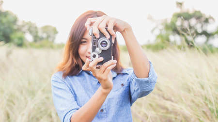 Woman photographed in a meadow with a camera.の写真素材
