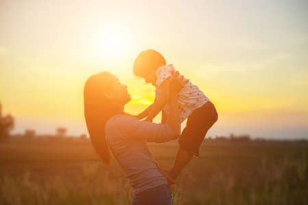 Mother encouraged her son outdoors at sunset, silhouette conceptの写真素材