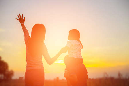 Mother encouraged her son outdoors at sunset, silhouette conceptの写真素材