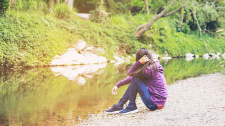 Lonely sad woman hug her knee and cry in the parkの写真素材