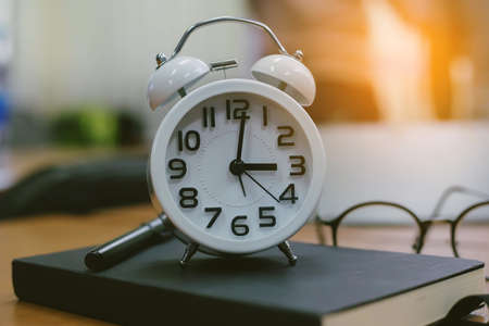 retro clock time at 9 o'clock with notebook or memo on wood table, times of memory writing diary concept vintage color tone.の写真素材