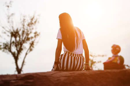 Sad young girl sitting alone on a grass outdoors,Sadness. Lonelinessの写真素材