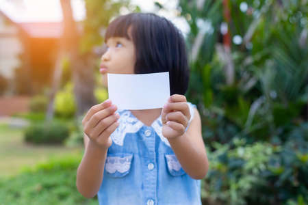 Happy girls showing blank credit card looking at side in a park with a green backgroundの写真素材