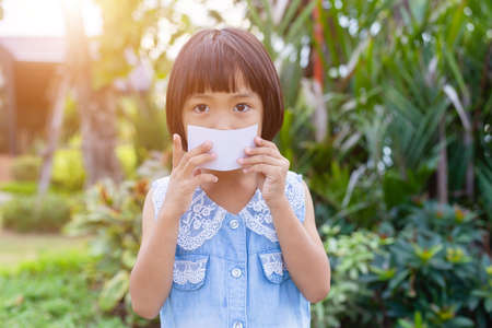 Happy girls showing blank credit card looking at side in a park with a green backgroundの写真素材